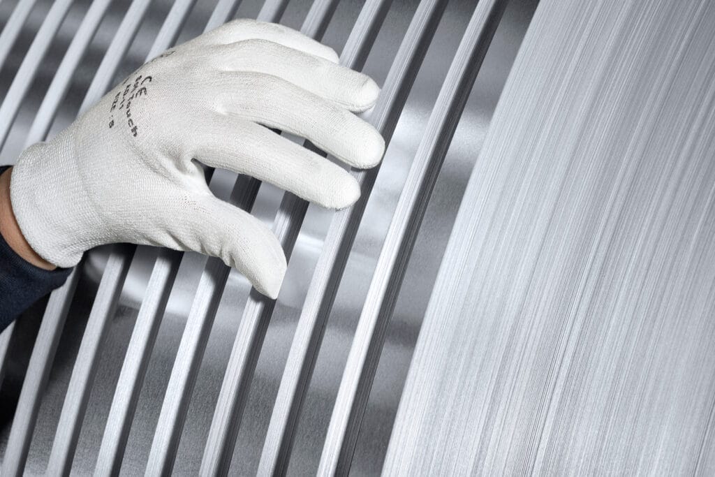 A person processes a metal piece in front of a large industrial looking tube.